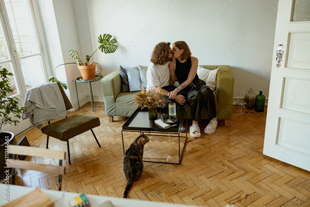 Happy couple hugging and kissing with love and tenderness in indoor living room leisure activity - obrazy, fototapety, plakaty 