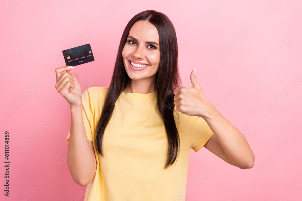 Photo of confident lucky lady wear yellow t-shirt showing thumb up rising bank card isolated pink color background Photo of confident lucky lady wear yellow t-shirt showing thumb up rising bank card isolated pink color background