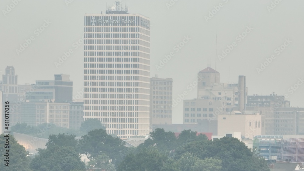 Fototapeta premium Poor air quality in Rochester NY caused by Canadian wildfire smoke over the city skyline dense around downtown office buildings due to climate change conditions in Canada