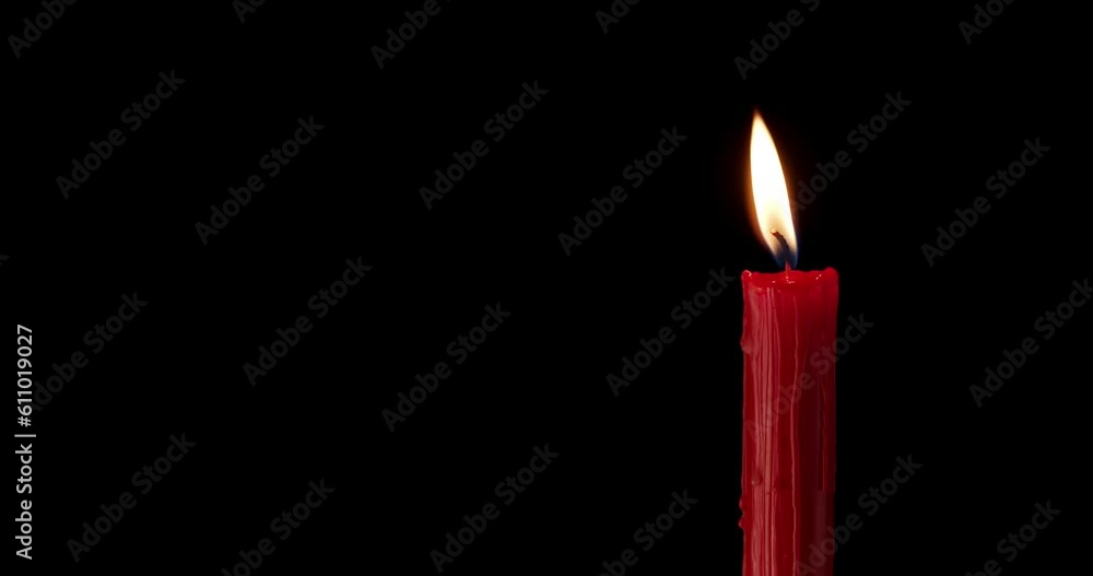 A single red candle burning. Isolated candle burning with dark background. Red paraffin candle with yellow shades burns on a black background. slow motion A single red candle burning. Isolated candle burning with dark background. Red paraffin candle with yellow shades burns on a black background. slow motion