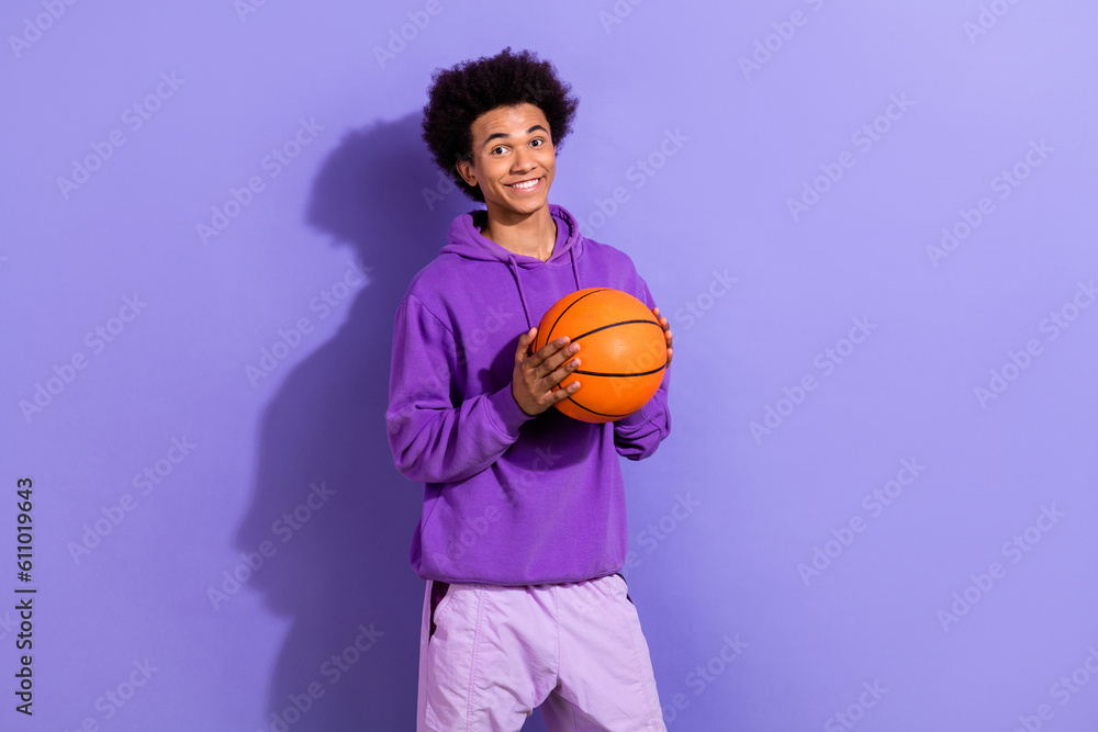 Photo of cheerful nice person toothy smile hands hold basketball empty space isolated on violet color background