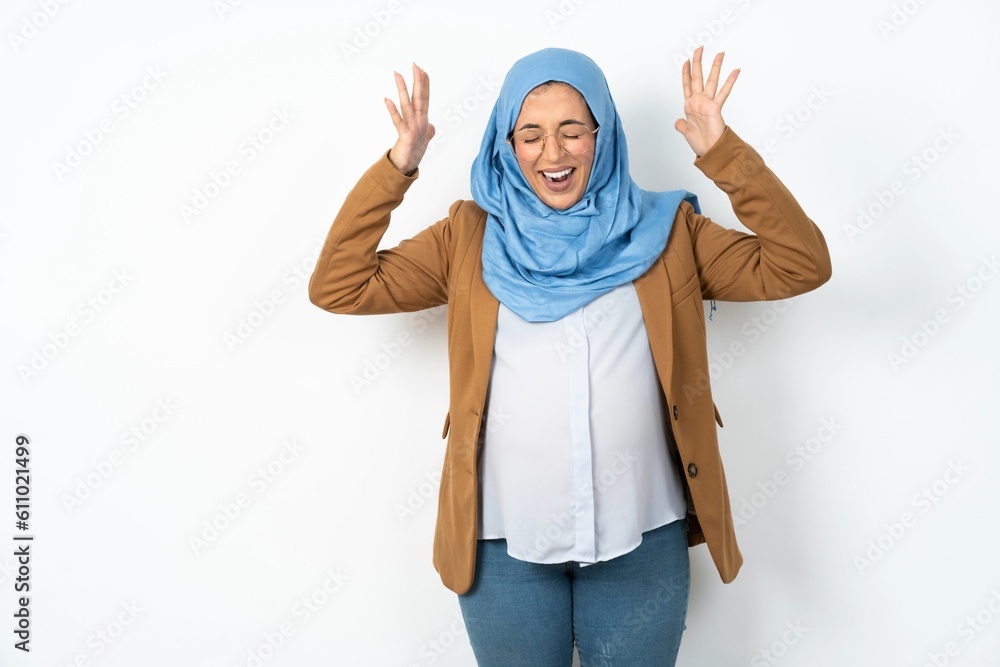 Young beautiful pregnant muslim woman wearing hijab over white background goes crazy as head goes around feels stressed because of horrible situation Young beautiful pregnant muslim woman wearing hijab over white background goes crazy as head goes around feels stressed because of horrible situation