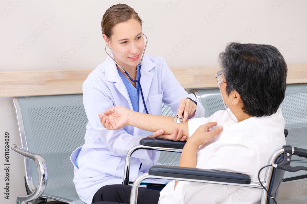 Fototapeta premium Female doctor caring for an elderly woman patient sitting in a wheelchair.