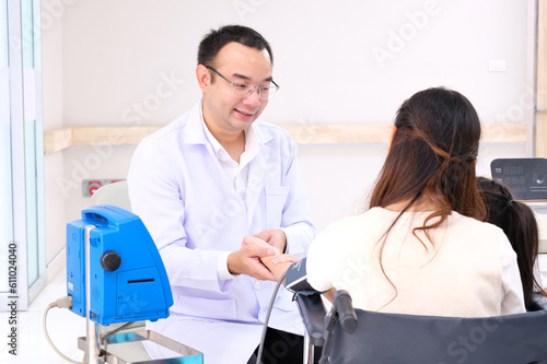 Asian male doctor measuring blood pressure for a female patient.