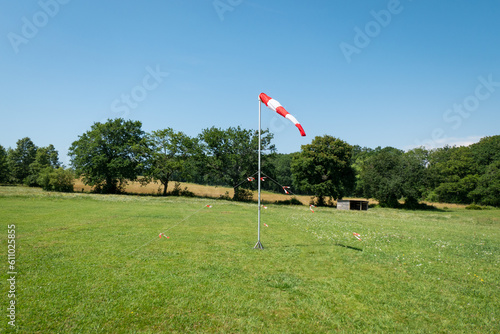 Cone giratório que indica a direção do vento colocado num locar de pouso para a prática de paraquedismo a meio a algumas árvores e verde relva photo