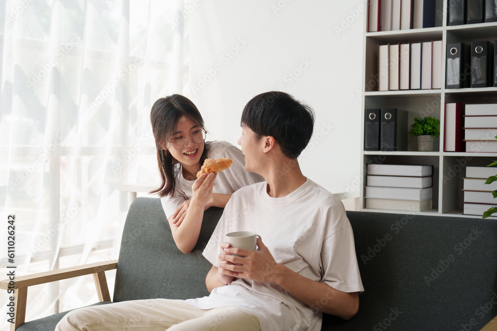 Fototapeta premium Beautiful asian couple in love and smiling sitting on sofa at morning. Romantic moment, relationships, family concept