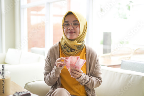 business Asian hijab woman wear Orange shirt show counting money