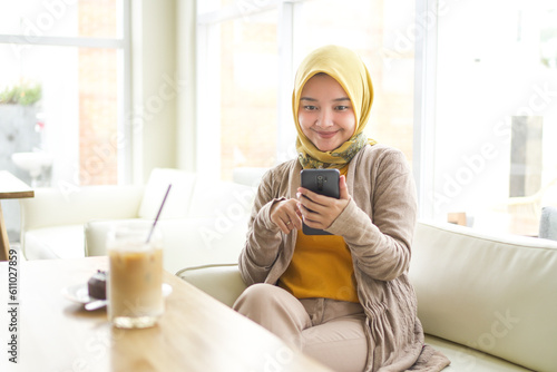 Business asian hijab woman wearing Orange T-shirt holding mobile phone