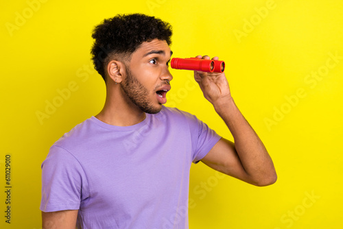 Side photo of funny guy bristle hold handheld optical lenses binoculars look shocked empty space view isolated on yellow color background