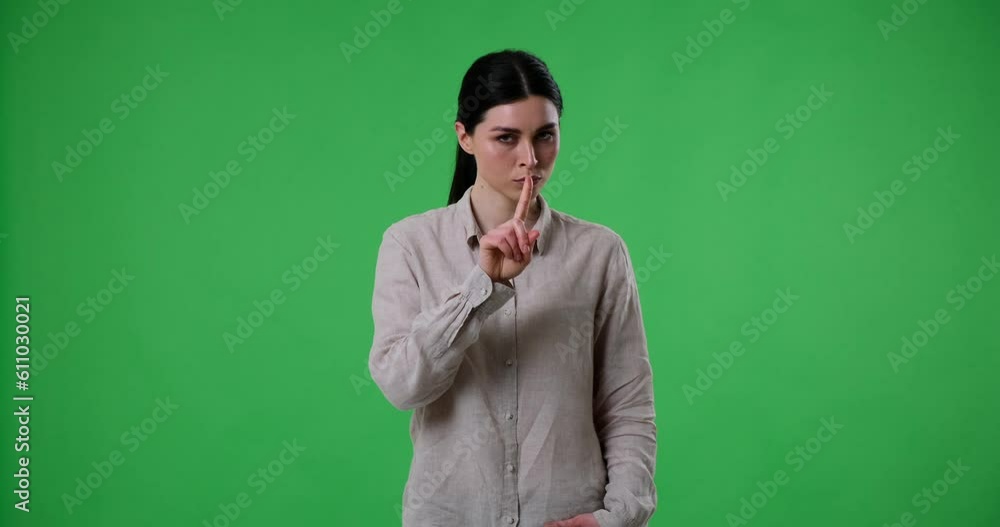 A dissatisfied Caucasian woman stands on a green screen and shows the hush gesture with her finger near her lips. She then shakes her finger and head in disapproval, forbidding something. A dissatisfied Caucasian woman stands on a green screen and shows the hush gesture with her finger near her lips. She then shakes her finger and head in disapproval, forbidding something.