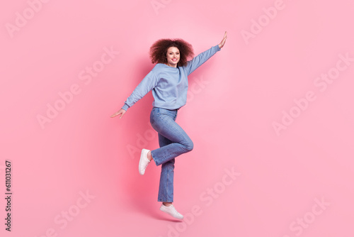 Full length photo of carefree excited woman dressed blue sweatshirt jumping high rising hands isolated pink color background © deagreez