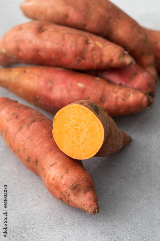 Raw sweet potatoes whole and cut. Orange kumara, sweet potato. Harvesting of root crops.  - obrazy, fototapety, plakaty 
