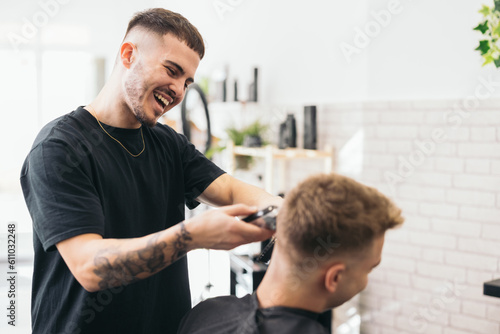 Young barber cutting hair with machine
