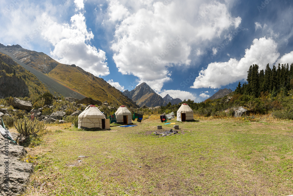 Yurts on wild meadows in Kyrgyzstan, Central Asia, Meadows and yurts on a grteen grass with blue cloudy sky. 
Unleash Your Wanderlust: Captivating Yurts and Majestic Meadows of Kyrgyzstan