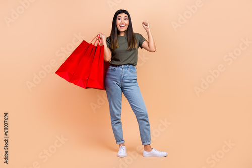 Full length photo of korean model young woman fist up celebrate sale proposition offer win promo code isolated on beige color background