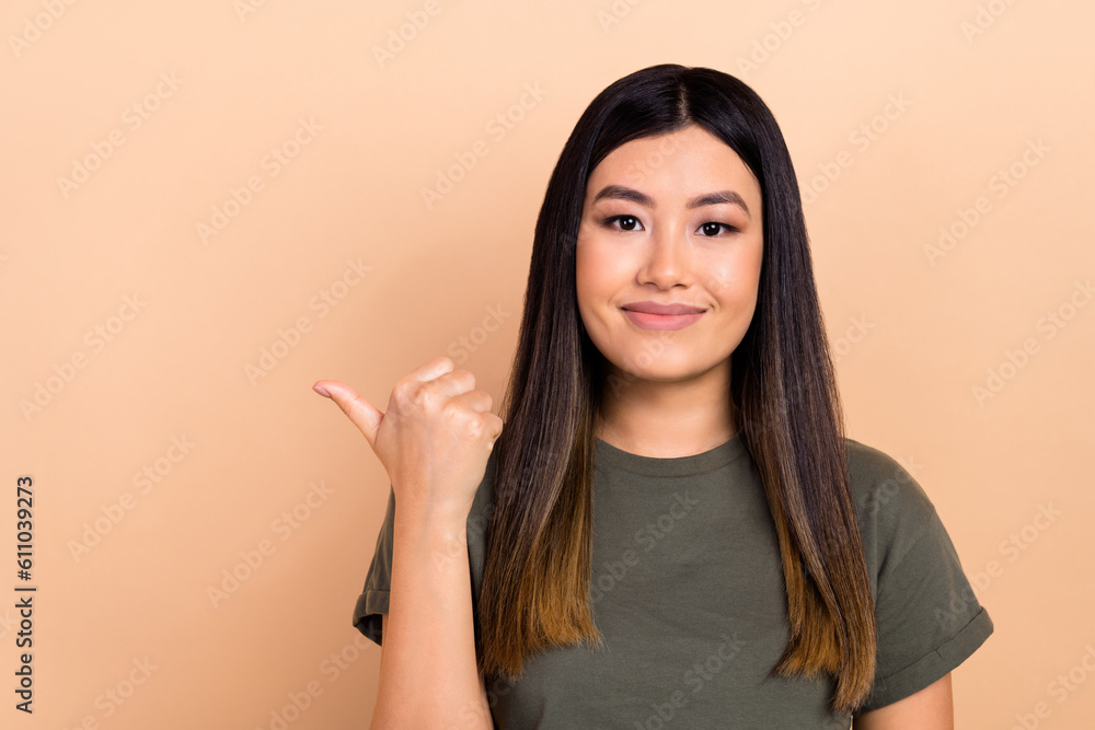 Photo of charming cheerful asian girl direct thumb finger empty space spa salon adv ads isolated beige pastel color background Photo of charming cheerful asian girl direct thumb finger empty space spa salon adv ads isolated beige pastel color background