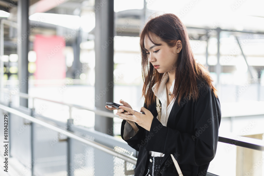 Young woman in black suit is using smartphone. Chatting. Online working. in public places. Female find information map location on mobile phone. Young woman in black suit is using smartphone. Chatting. Online working. in public places. Female find information map location on mobile phone.