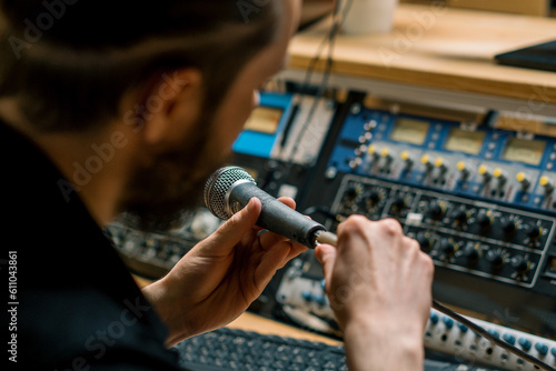sound engineer connects microphone to music equipment in professional recording studio close-up of hands
