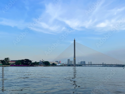Beautiful panoramic cityscape. Blue sky and water. Bangkok city. Amazing Thailand. Rama VIII Bridge crossing the Chao Phraya River. Reflection on the water surface. View to the bank. Pattern of clouds