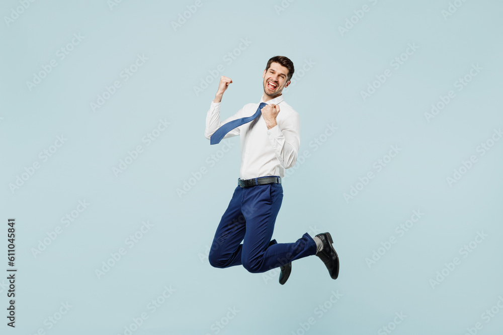 Full body young employee IT business man corporate lawyer in classic formal shirt tie work in office do winner gesture celebrate clenching fist say yes isolated on plain pastel light blue background
