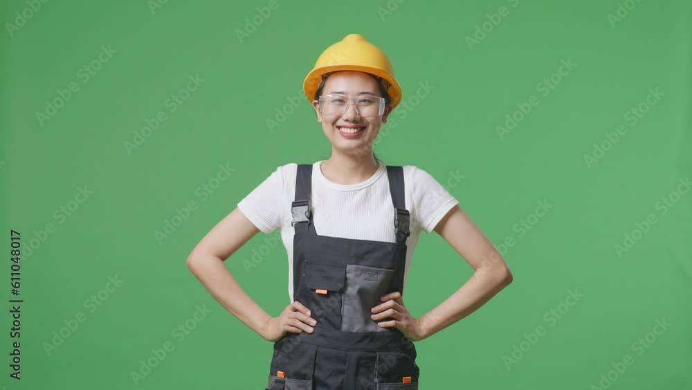 Asian Woman Worker Wearing Goggles And Safety Helmet Wiping The Sweat And Being Tired While Standing In The Green Screen Background Studio
