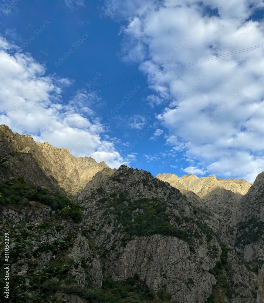 High rocky mountains against a pleasant blue sky in the daytime 