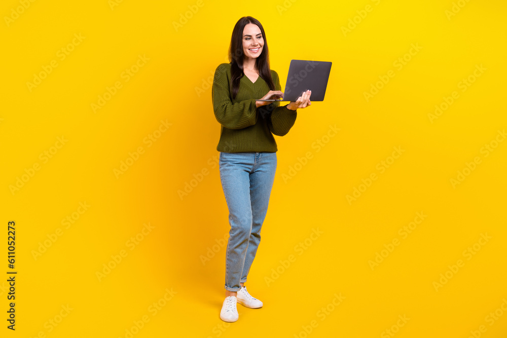 Full length photo of cheerful nice person use wireless netbook networking isolated on yellow color background Full length photo of cheerful nice person use wireless netbook networking isolated on yellow color background