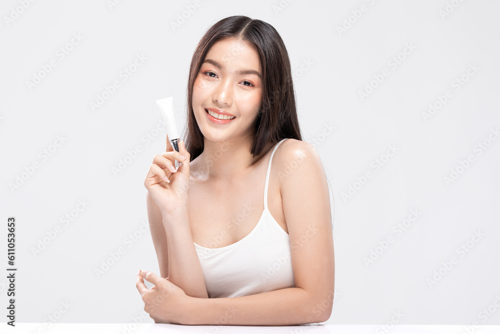Beautiful Asian woman with a radiant smile holding a blank tube, ready for your cosmetic or skincare branding. Confidence and elegance personified isolated on white background. Self Care Concept Beautiful Asian woman with a radiant smile holding a blank tube, ready for your cosmetic or skincare branding. Confidence and elegance personified isolated on white background. Self Care Concept