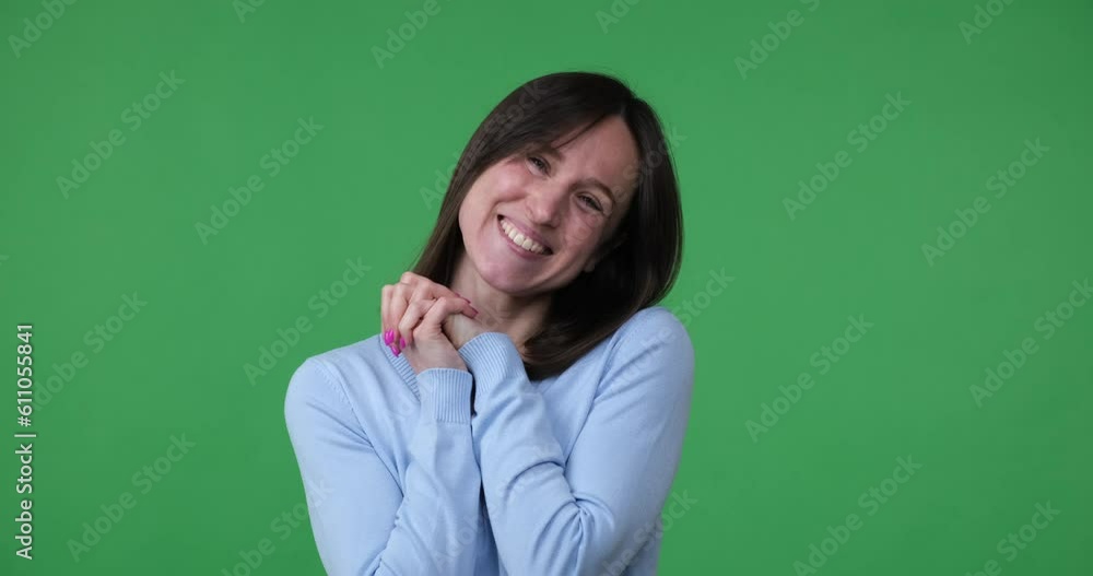 Caucasian woman standing on a green background, looking at the camera with a big smile. Suddenly, she looks amazed and surprised, as if she has discovered something incredibly cute and adorable. Caucasian woman standing on a green background, looking at the camera with a big smile. Suddenly, she looks amazed and surprised, as if she has discovered something incredibly cute and adorable.