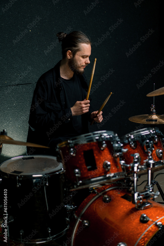 Obraz premium a young male drummer plays a drum kit in a recording studio at a professional musician's rehearsal recording a song