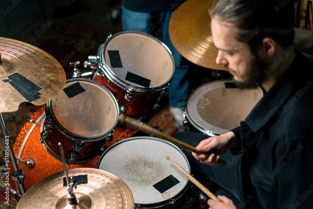 Obraz premium a young male drummer plays a drum kit in a recording studio at a professional musician's rehearsal recording a song