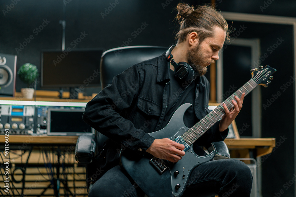 Obraz premium rock performer with electric guitar in recording studio recording playing own track musical instrument strings melody