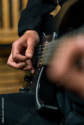 rock performer with electric guitar in recording studio recording playing own track creating song musical instrument strings close-up