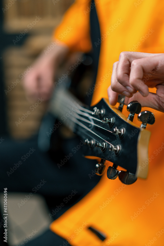 rock performer with electric guitar in recording studio recording playing own track tuning musical instrument strings close-up
