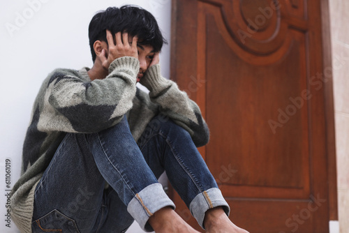Konstfotografi Depressed man sitting on the floor with head in hands and leaning against a wall