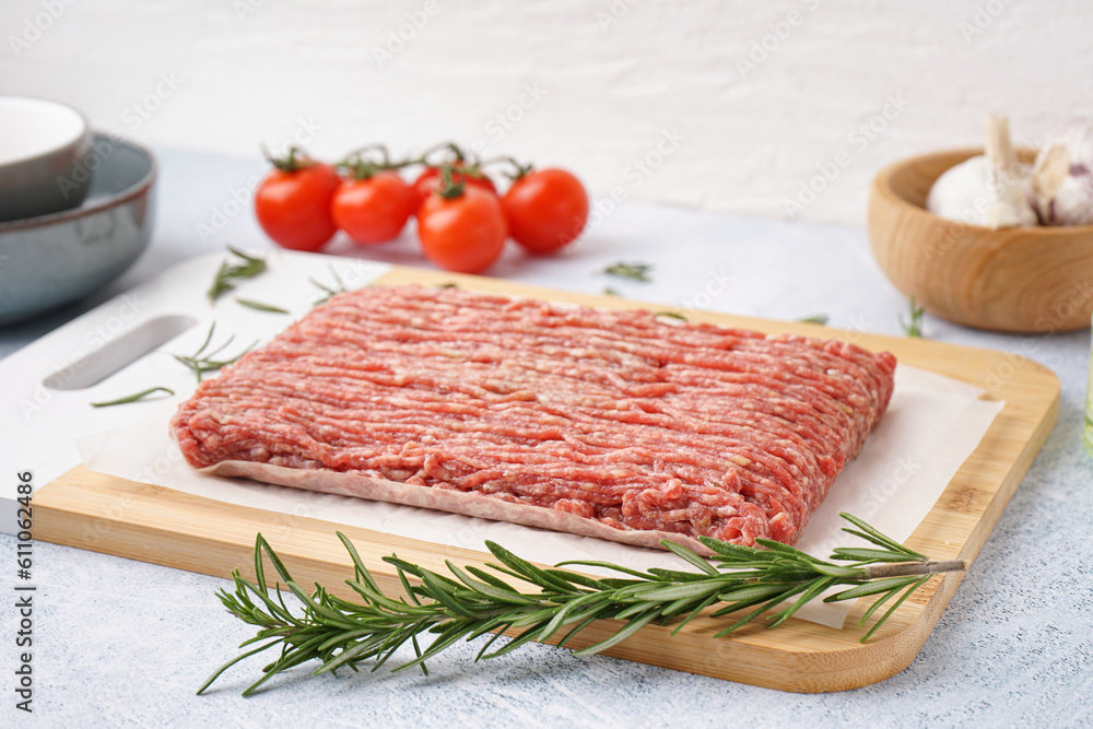 Board with fresh minced meat, rosemary and tomatoes on grey grunge background Board with fresh minced meat, rosemary and tomatoes on grey grunge background
