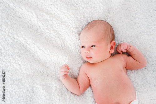 Little newborn baby boy lying on white bed