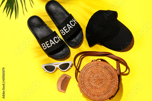 Stylish female flip-flops and accessories on yellow background