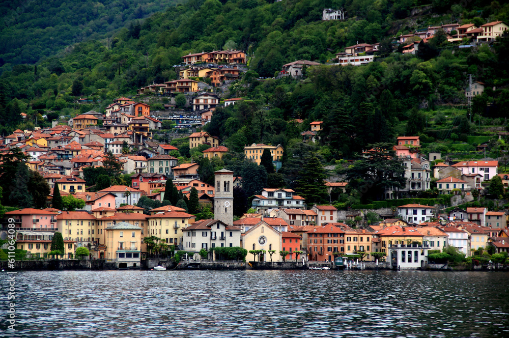 Landscape view of one of the many small towns on Lake Como with a church in the foreground and houses on a hillside during the rain in northern Italy