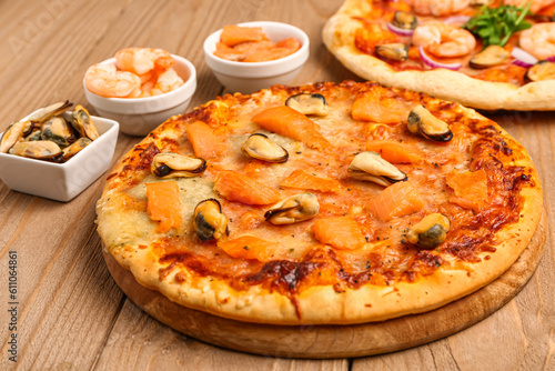 Board with tasty seafood pizza on wooden background