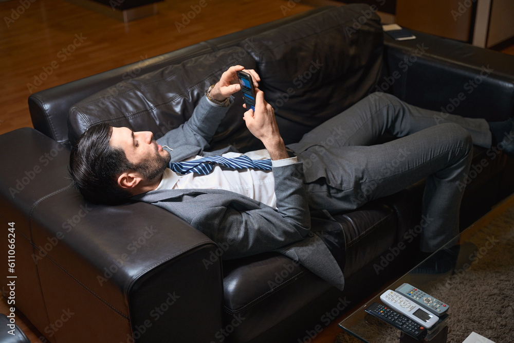 Fototapeta premium Man rests on a leather sofa in a hotel room