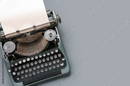 Vintage typewriter with blank paper sheet on grey background