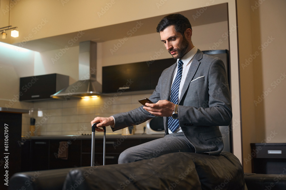 Man with mobile phone sat on back of leather sofa Man with mobile phone sat on back of leather sofa