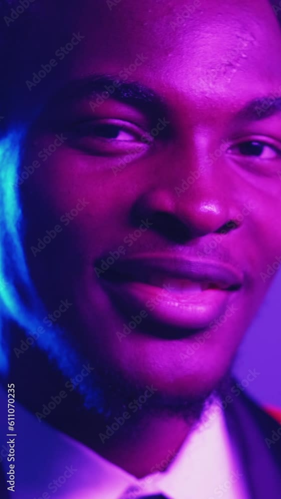 Vertical video. Dandy look. Man confidence. Party style. Blue purple color neon light face of proud smiling gentleman in tuxedo tie. Vertical video. Dandy look. Man confidence. Party style. Blue purple color neon light face of proud smiling gentleman in tuxedo tie.