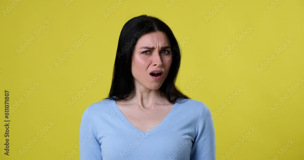 A Caucasian woman stands on a yellow background, looking at the camera. Suddenly, she sees something nasty and becomes disgusted, tilting her head away from the camera in disgust. A Caucasian woman stands on a yellow background, looking at the camera. Suddenly, she sees something nasty and becomes disgusted, tilting her head away from the camera in disgust.