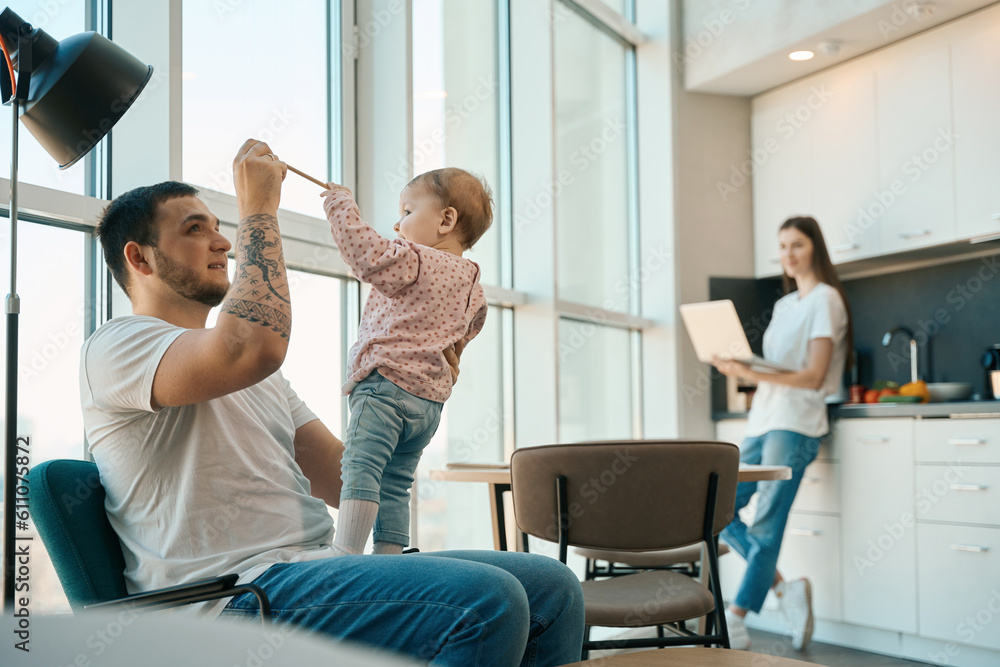 Obraz premium Dad and baby daughter play with a pencil