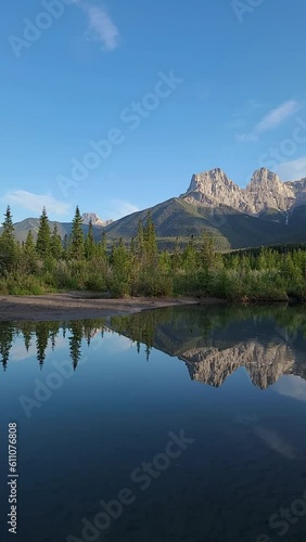 Mountain peaks reflecting in the calm water below at Three Sisters in Canmore, near Banff National Park, Canada in summer time with wilderness, wild, tourist, tourism area.