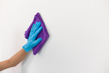 Young woman holding a cloth soaked with cleaning and disinfectant wipes on the surface of the house wall to remove dirt and help eliminate germs so that the walls of the house look clean and safe.