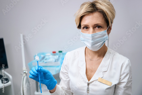 Gynecologist in mask holds brush to take smear from cervix