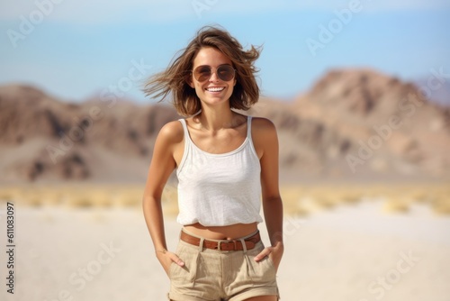 Medium shot portrait photography of a glad girl in her 30s wearing breezy shorts against a desert landscape background. With generative AI technology